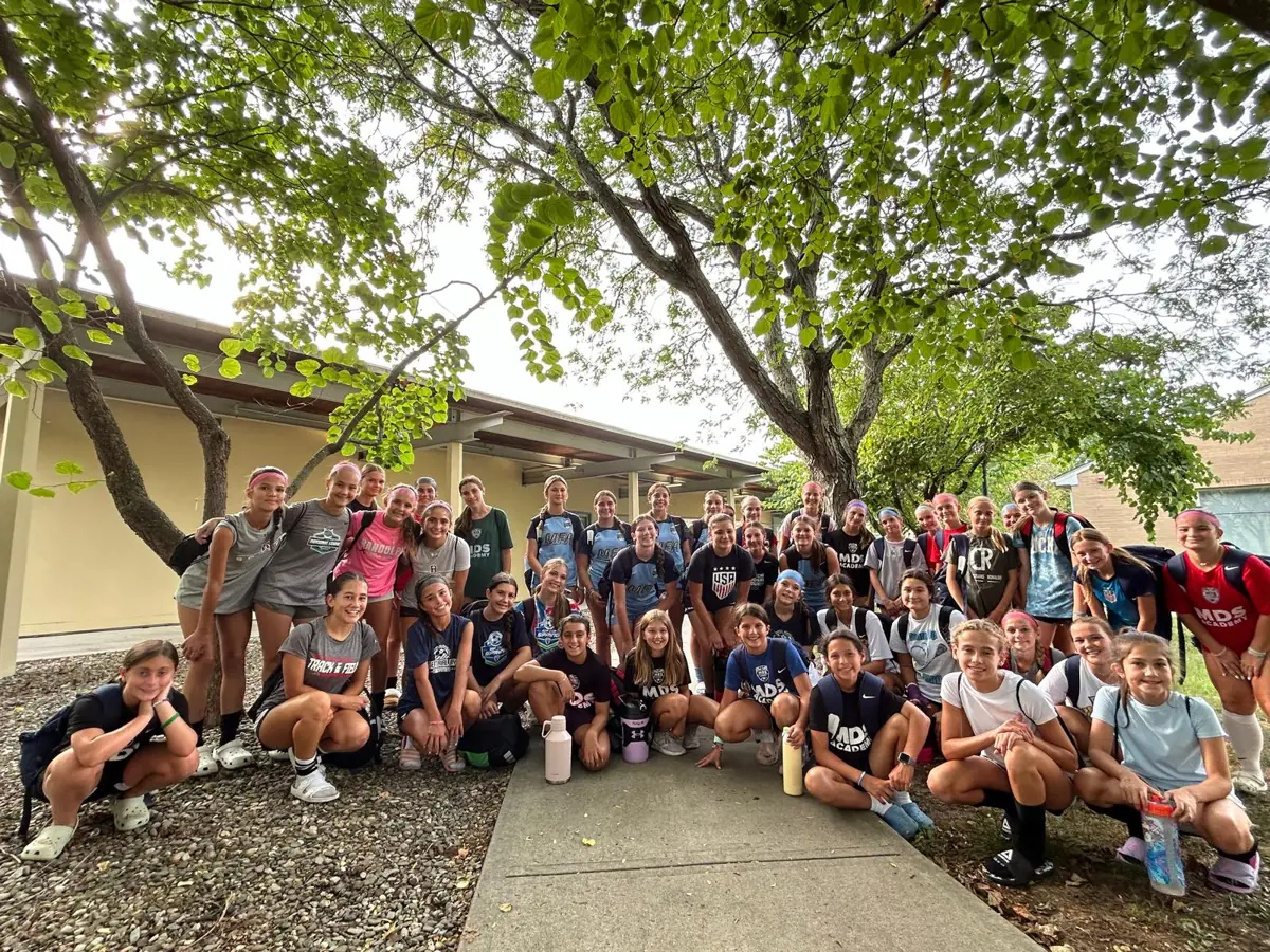 Campers and coaches in a group photo under the trees