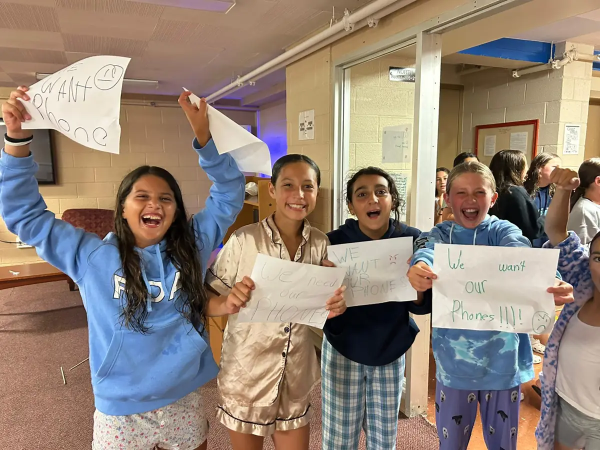 Campers holding up signs in the dorms